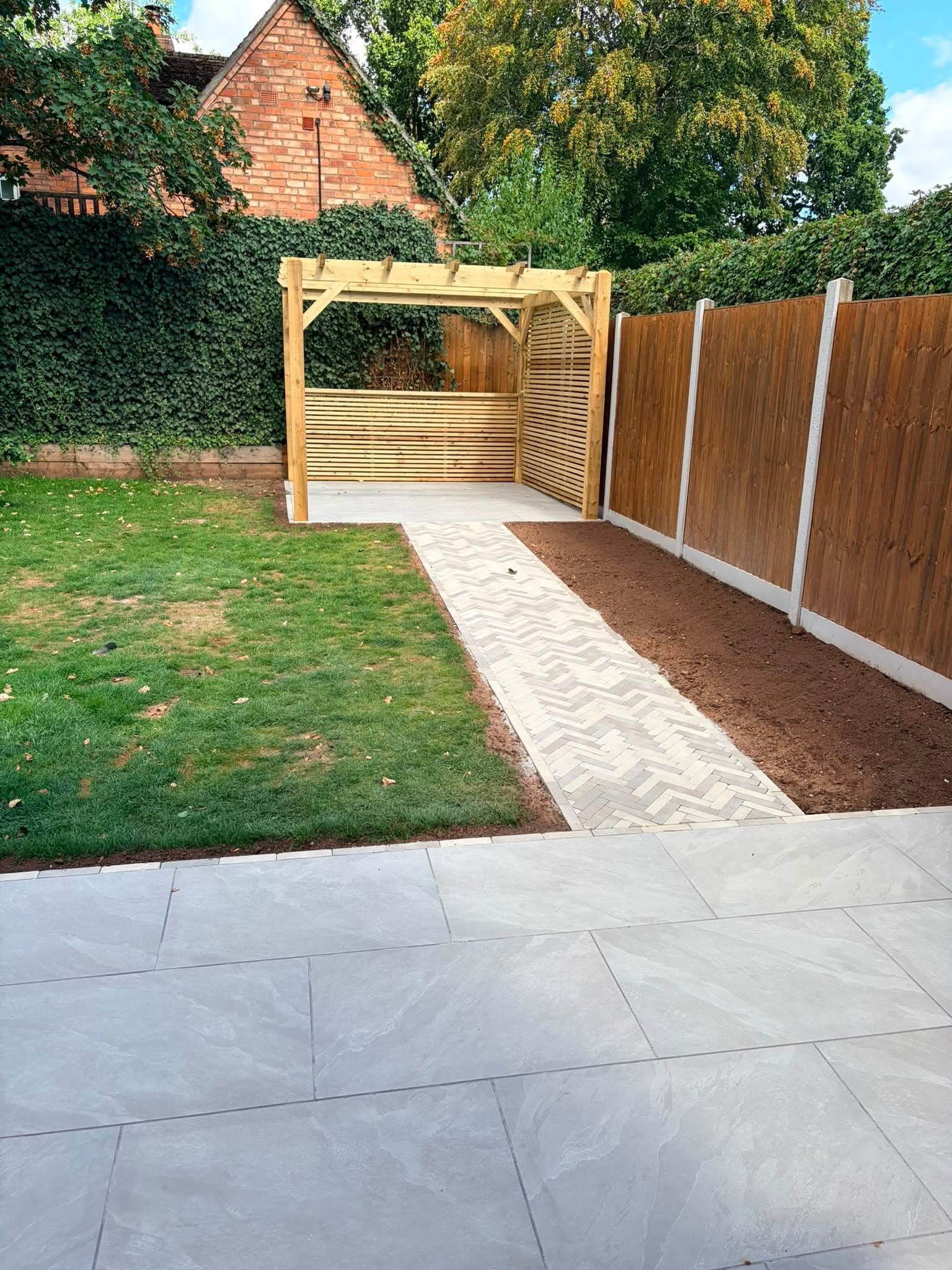 Landscaped garden with paved path, lawn and timber pergola