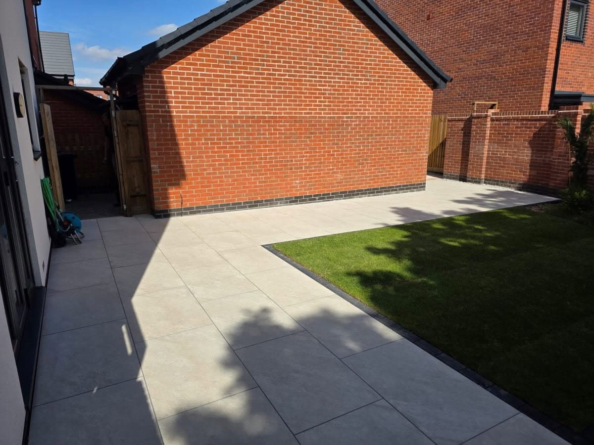 Paved patio beside a lawn in a modern rear garden