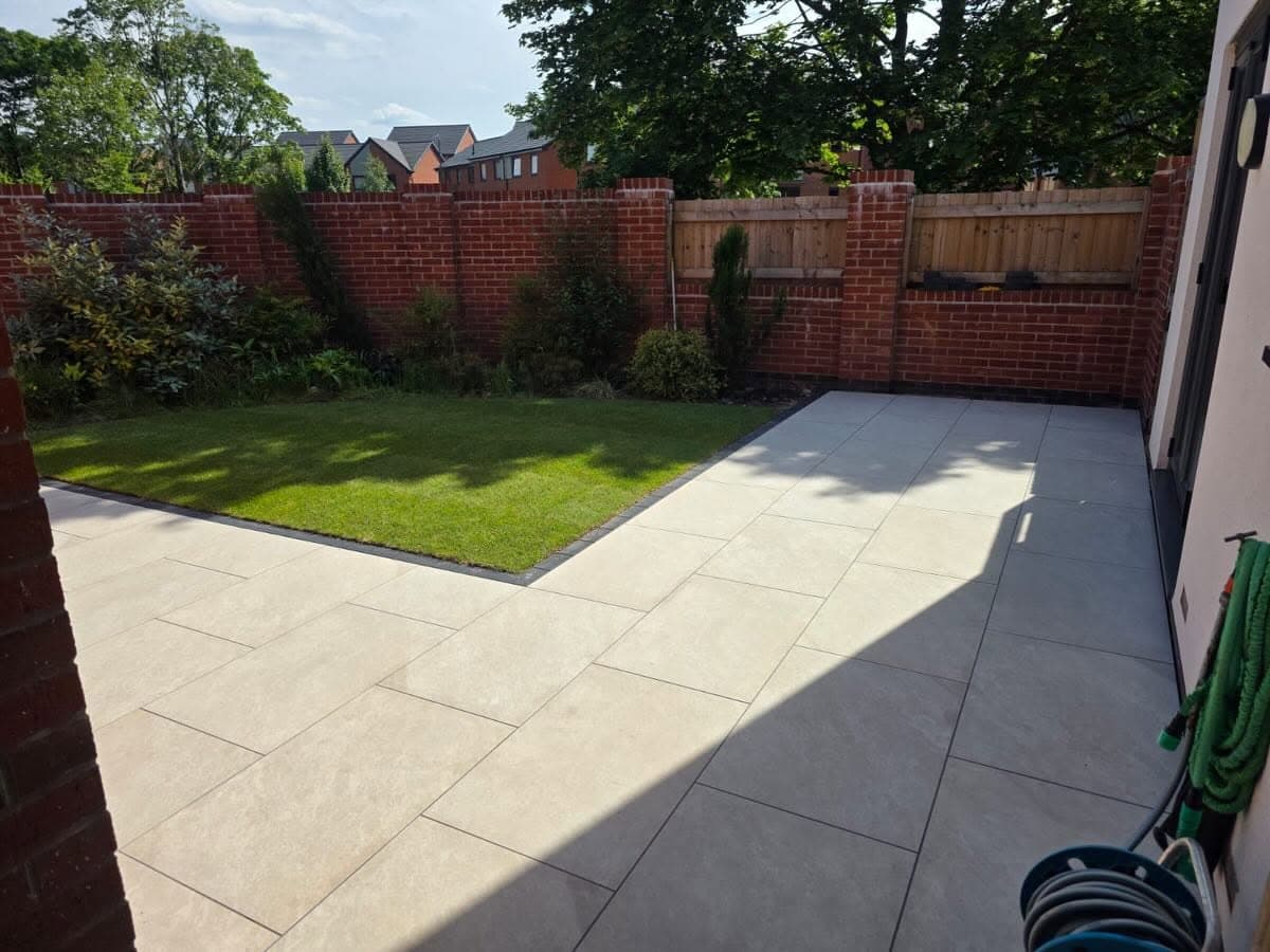 Light paved patio wrapped around a neat garden lawn